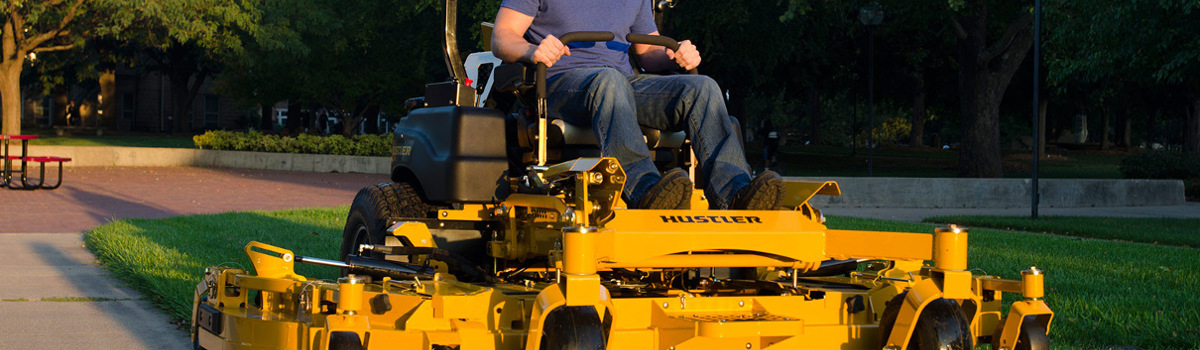 Person mowing grass in a park on a Hustler® lawn mower 